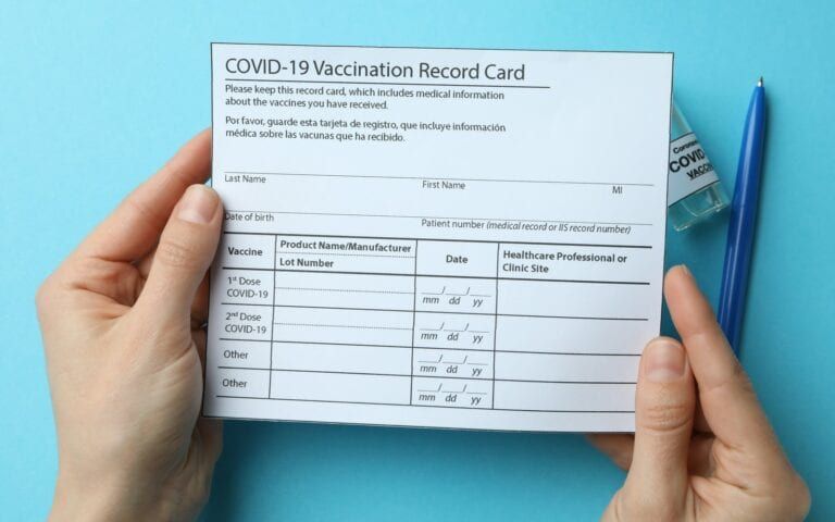 Woman holding a COVID Vaccination Record